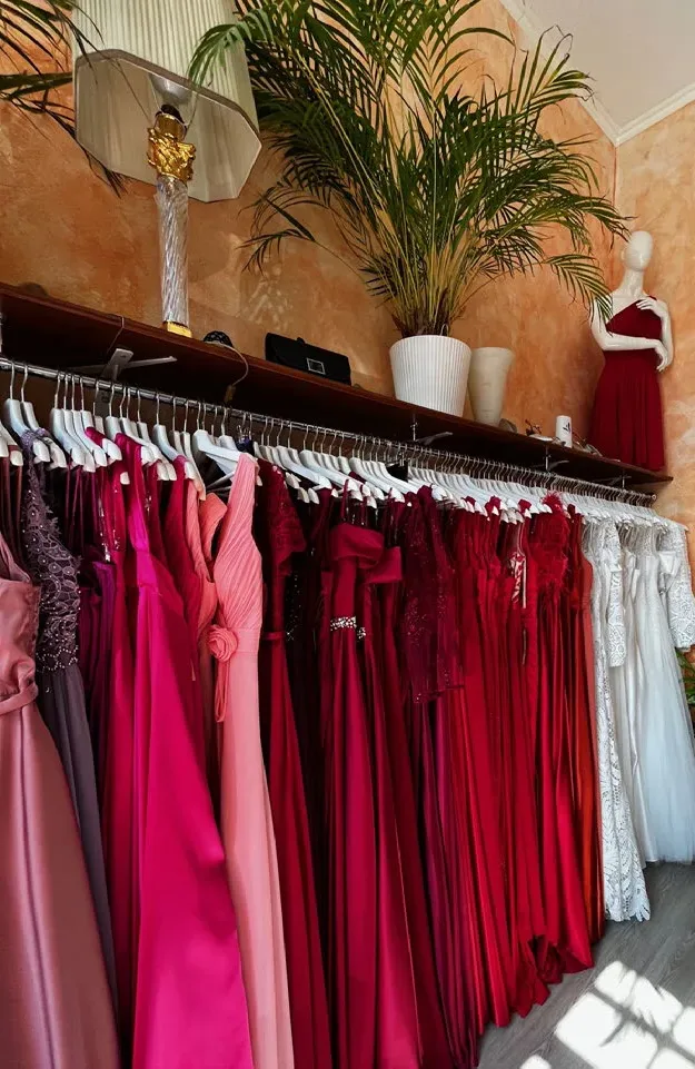 Intérieur de LK Boutique : robes de soirée rangées par couleur, du rose au rouge